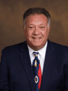 A man in a suit and tie smiling for the camera.