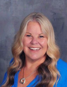 A woman with long blonde hair wearing blue shirt.