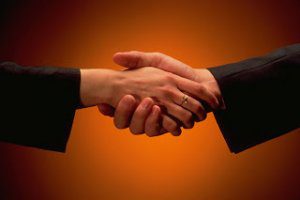 Two people shaking hands in front of an orange background.